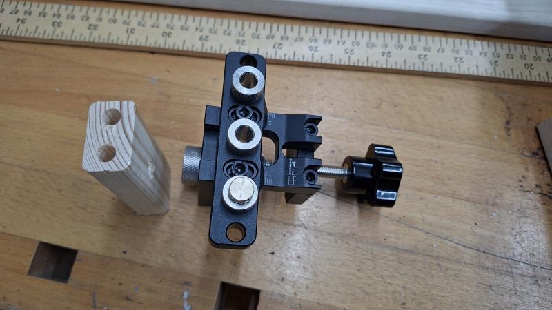 Dowel jig next to slat off-cut with dowel holes drilled in it